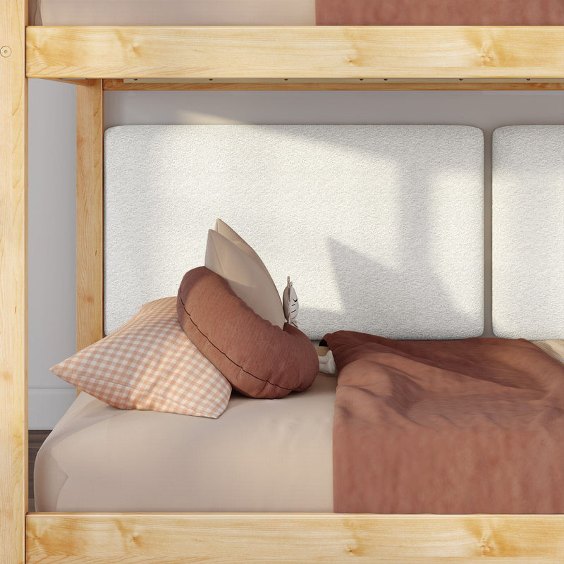 Wooden bunk bed with padded white headboard, rust-colored duvet, gingham pillow, round cushion and small white alarm clock