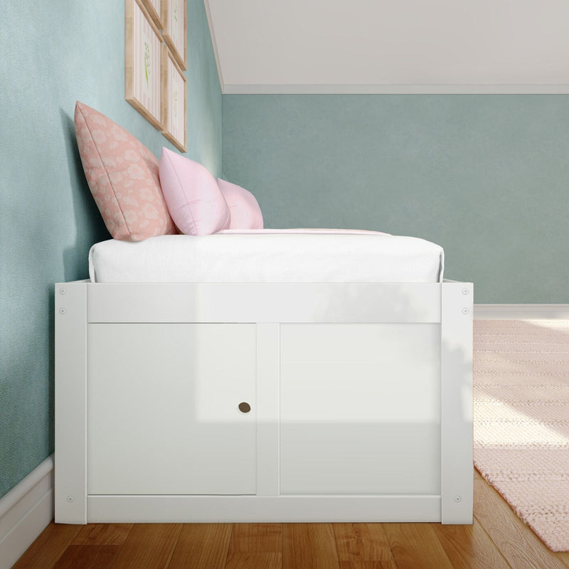 Pastel kids bedroom with white wooden storage bed, pink floral and blush pillows, teal textured accent wall, framed botanical prints and hardwood floor for modern nursery decor
