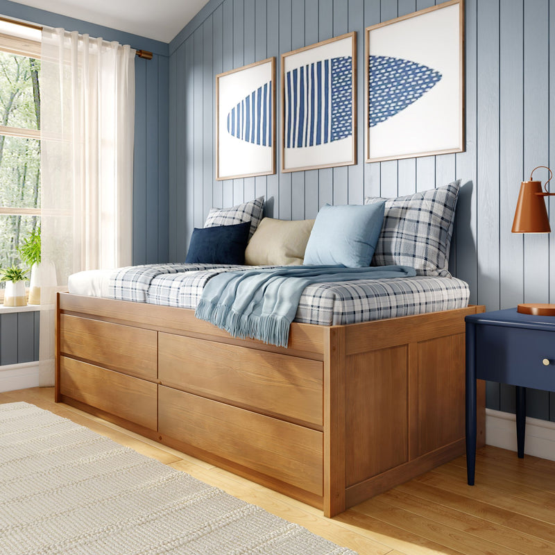 Cozy coastal bedroom with wooden platform bed and storage drawers, plaid blue pillows, light-blue shiplap walls and triptych blue artwork