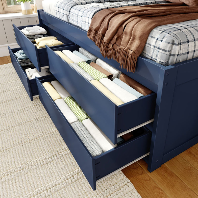 Blue storage bed with under-bed drawers holding rolled linens and blankets, plaid mattress and brown throw — space-saving bedroom storage solution