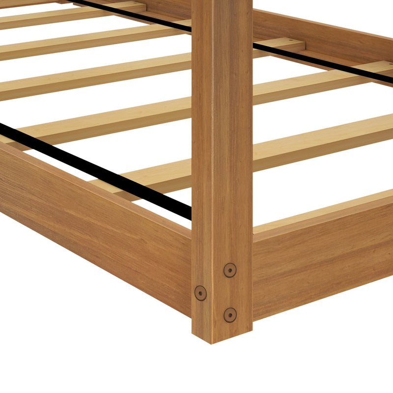 Close-up of oak wooden platform bed frame corner with natural finish, evenly spaced wood slats, black center support straps and sturdy corner post with hex bolts