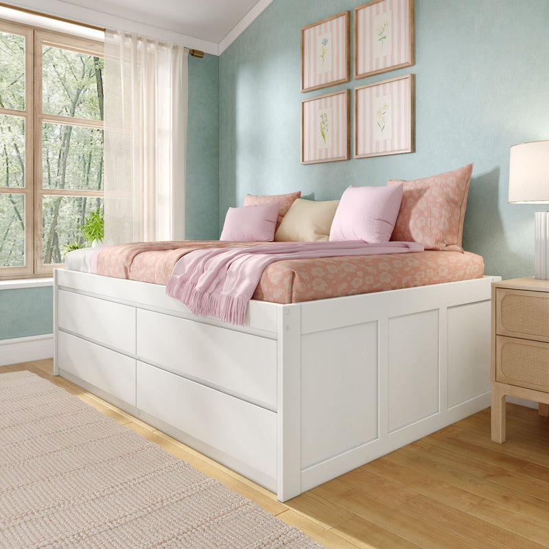 Sunlit pastel bedroom with white storage bed, pink floral bedding and pillows, teal accent wall, framed botanical prints, sheer curtains and hardwood floor