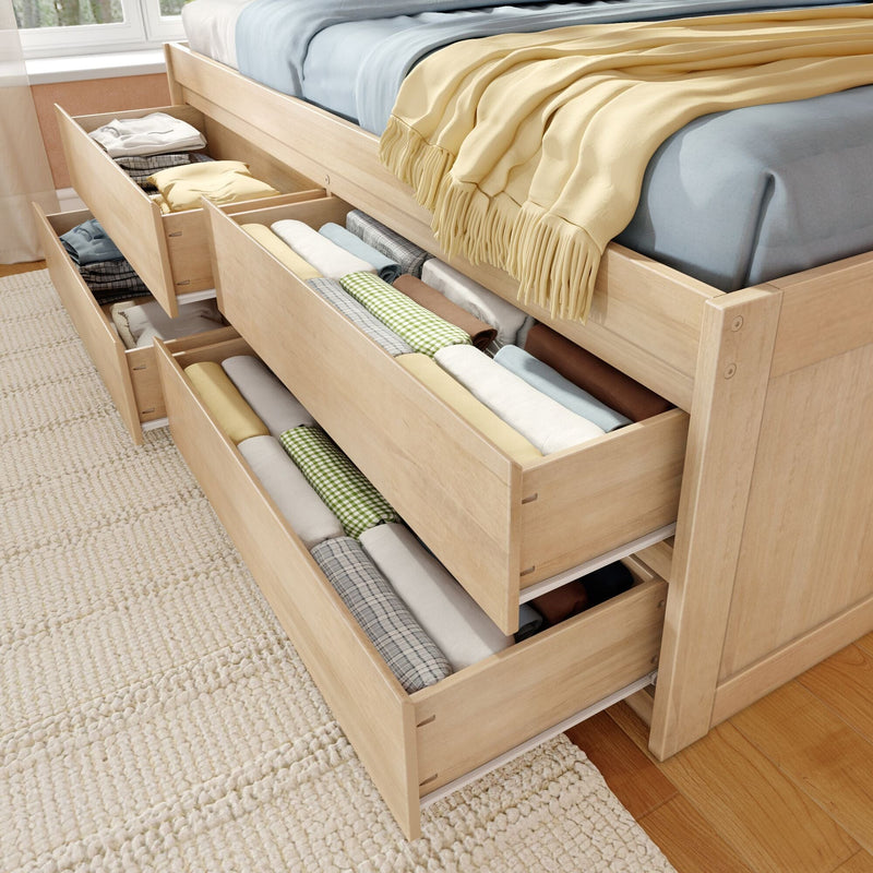 Space-saving wooden storage bed with multiple under-bed pull-out drawers neatly storing folded linens, pillows and blankets in a bright bedroom