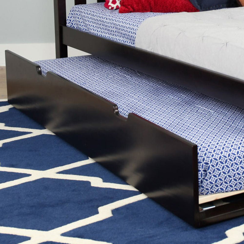 Dark wood twin trundle bed with pull-out mattress and blue patterned bedding on navy geometric rug — space-saving underbed storage for kids' bedroom