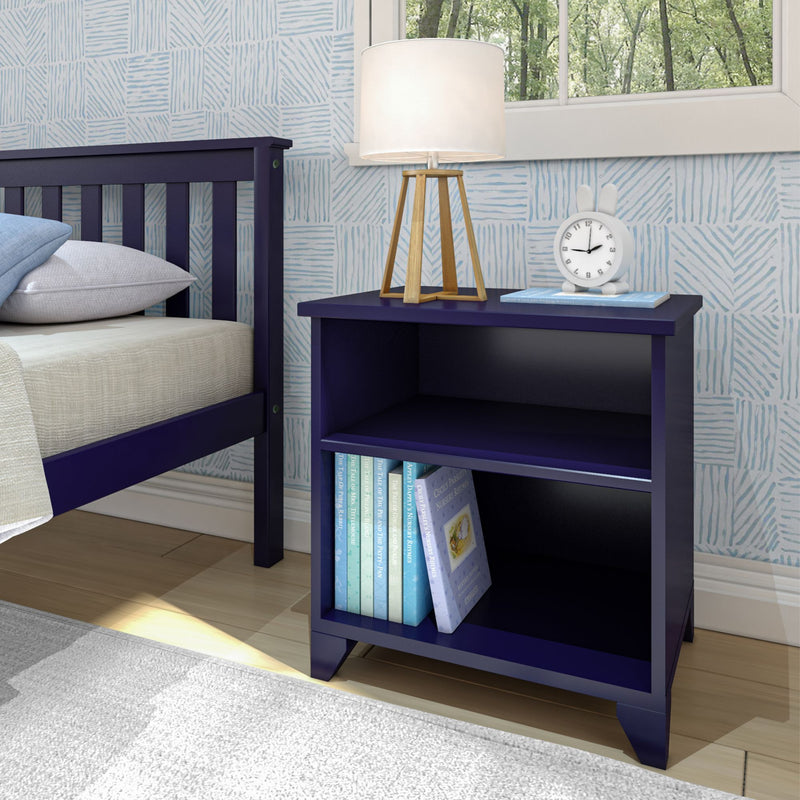 Navy blue nightstand beside bed with wooden tripod lamp, bunny alarm clock and children's books against light blue patterned wallpaper