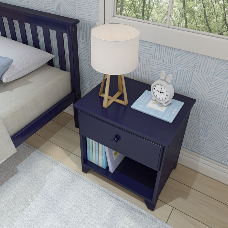Navy blue nightstand with wooden tripod lamp and white shade, bunny alarm clock and Peter Rabbit book in child's bedroom