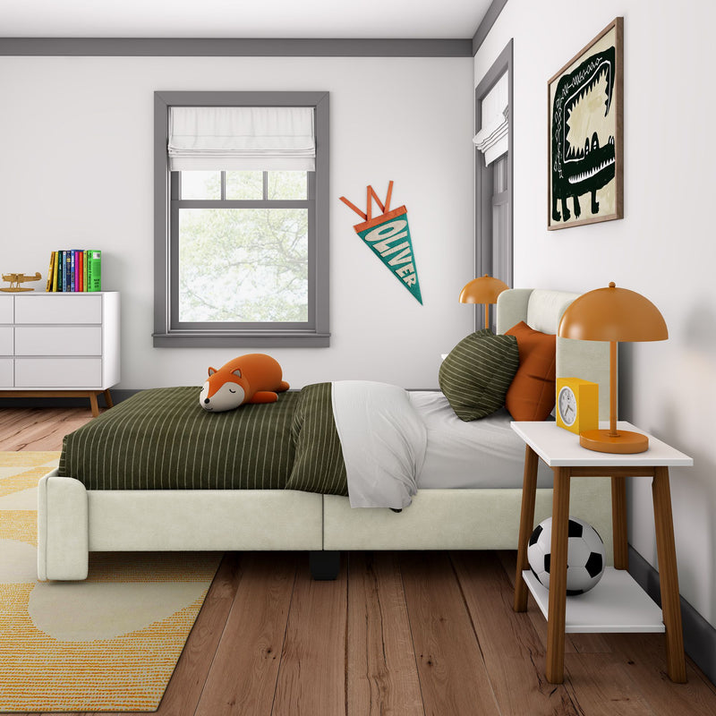 Modern kids bedroom decor with green striped bedding and fox plush toy, orange bedside lamps, personalized "Oliver" pennant, dinosaur wall art, white dresser with colorful books, soccer ball, and large windows with roman shades
