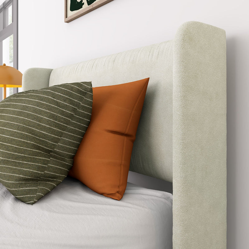 Cream upholstered headboard close-up with green striped and terracotta orange accent pillows on white bedding — modern bedroom decor