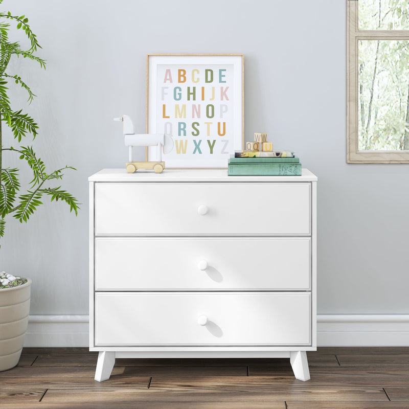 White nursery dresser with framed pastel alphabet print, wooden pull toy, alphabet blocks and books beside a potted plant by a window — modern children’s room decor