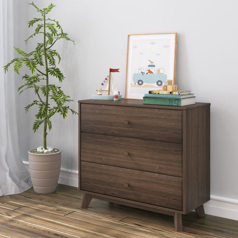 Mid-century modern dark wood dresser styled for a children's nursery with a potted indoor plant, toy sailboat, framed animal van print, stacked books and wooden blocks