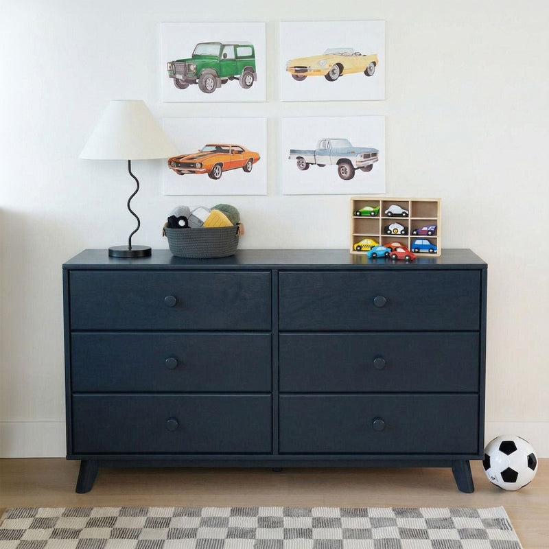 Navy blue six-drawer dresser in kids' bedroom with lamp, toy basket, wooden toy car organizer, car-themed wall art, soccer ball and checkered rug