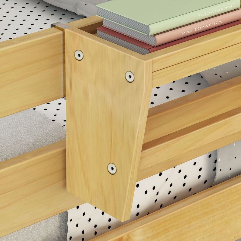 Close-up of natural pine wooden bunk bed corner with slatted rails, mattress and black polka-dot fitted sheet, stacked pastel hardcover books on top