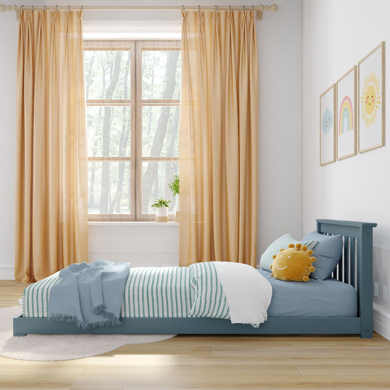 Sunlit kids bedroom nursery with teal bed and striped bedding, yellow curtains, smiling sun pillow, framed rainbow and cloud wall art, and potted plant on the windowsill