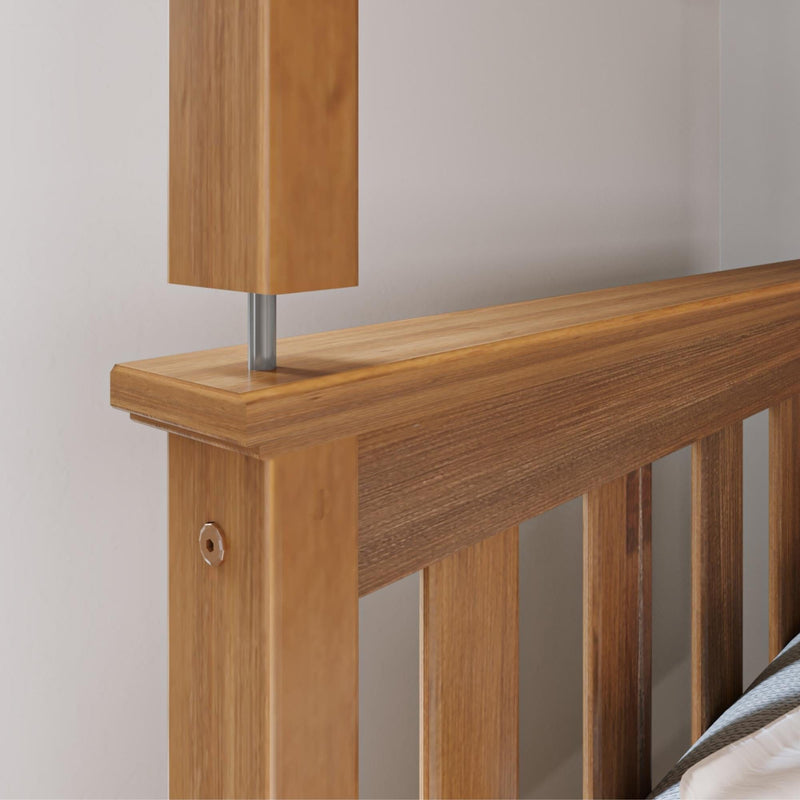 Close-up of solid oak bed headboard with natural wood grain, corner post and metal support rod showing modern wooden bed frame detail