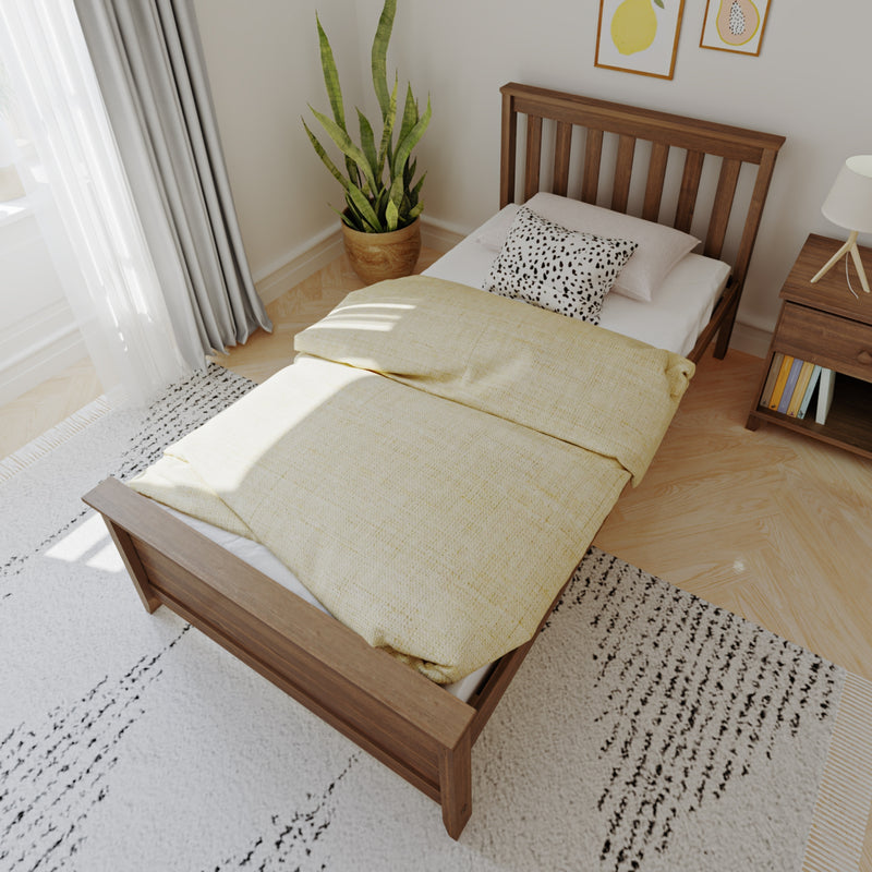 Modern minimalist bedroom interior with wooden slatted bed frame, yellow duvet, spotted accent pillow, bedside table and potted snake plant by a sunlit window.
