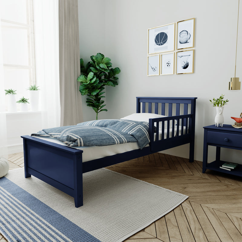 Navy blue twin bed in kids' bedroom with blue striped bedding, matching nightstand, sports-themed framed wall art, fiddle-leaf fig and white curtains
