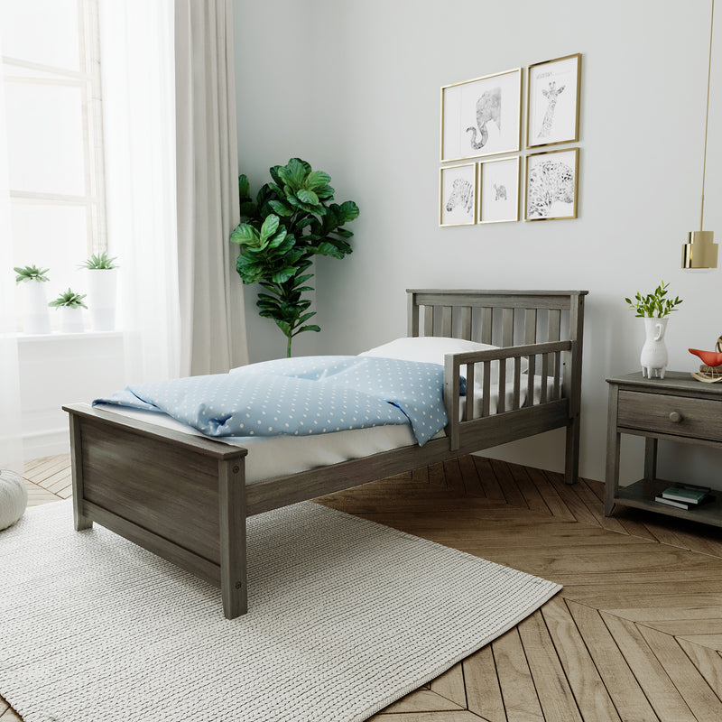 Scandinavian nursery interior with wooden toddler bed, blue polka-dot bedding, leafy potted plants, framed gallery wall art and soft natural light