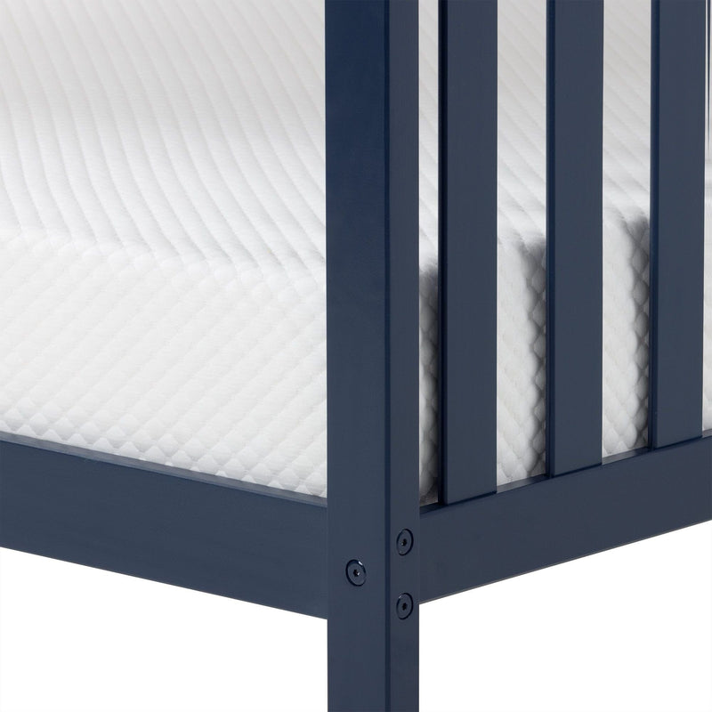 Close-up of white quilted mattress corner inside navy blue wooden bed frame showing mattress texture and slatted support
