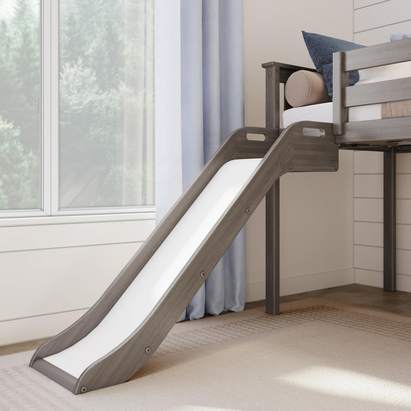 Modern gray wooden kids bunk bed with slide, blue pillows and light curtains in a sunlit children's bedroom