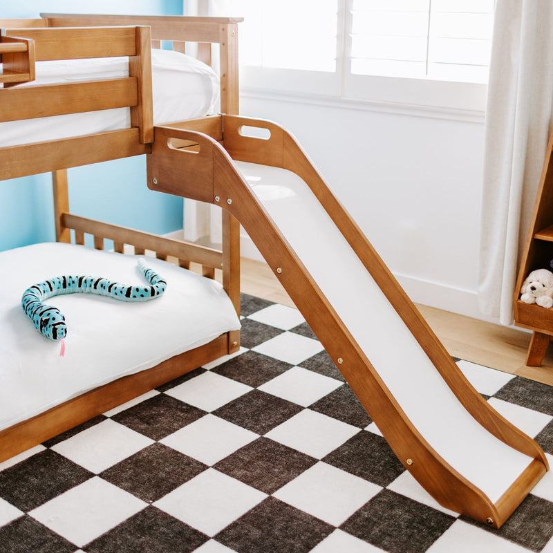 Modern wooden kids bunk bed with slide, white bedding and black-and-white checkerboard rug in a bright children's bedroom