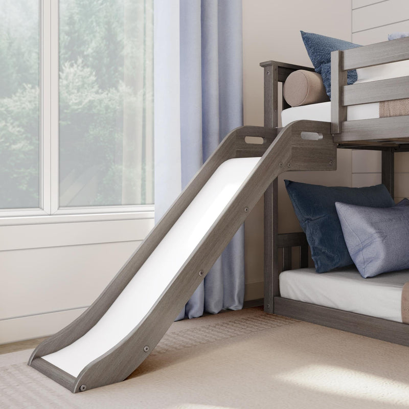 Children's gray wood bunk bed with slide, blue pillows and light curtains in a sunlit kids' bedroom by a window