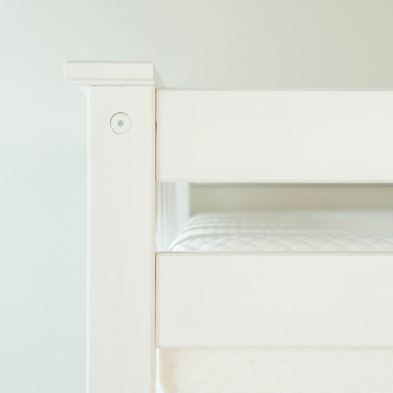 Close-up of white wooden bunk bed frame corner with visible screw and mattress edge, modern minimalist bedroom furniture detail