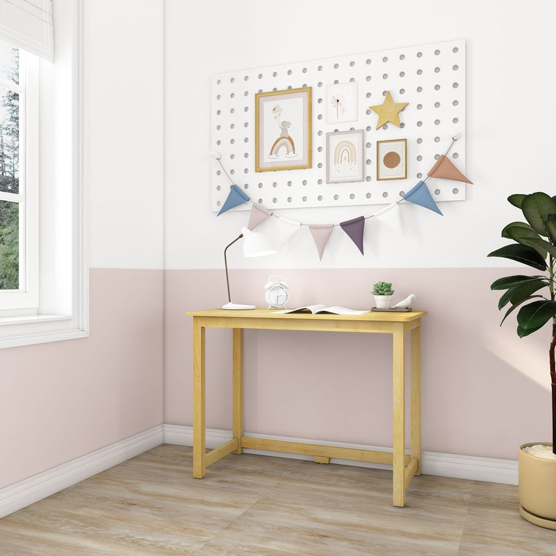 Minimalist children's nursery wall with a white pegboard displaying framed pastel rainbow artwork and a wooden star, pastel fabric bunting above a light wood desk with a white lamp, alarm clock and potted succulent, soft pink-and-white walls and indoor plant by the window