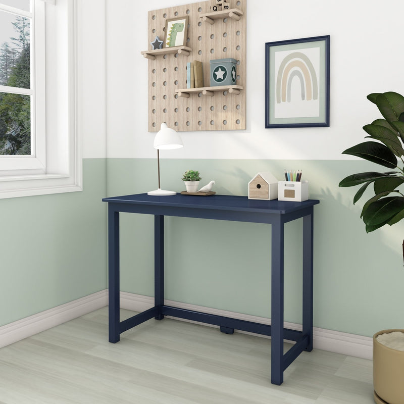 Children's study nook with navy blue desk, wooden pegboard shelves, white desk lamp, pastel mint wall and framed rainbow wall art