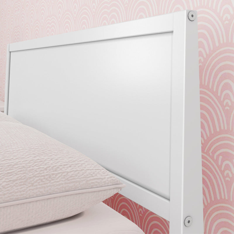 Close-up of white wooden bed headboard with pale pink textured bedding and pink arch-pattern wallpaper, modern bedroom decor.