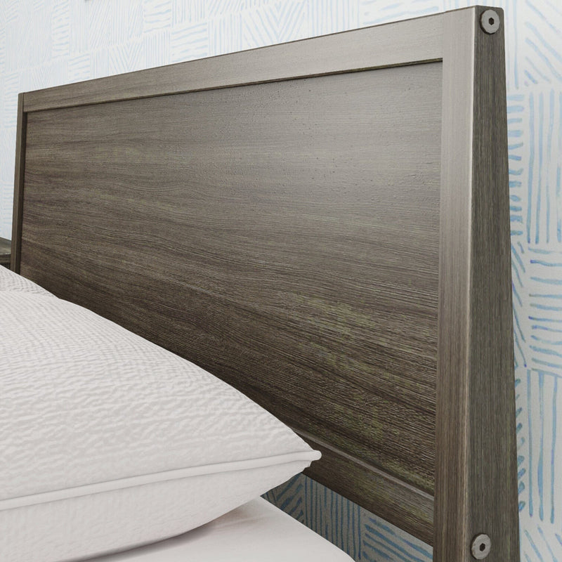 Close-up of modern gray wood headboard with textured grain, white bedding and blue patterned wallpaper in a bedroom