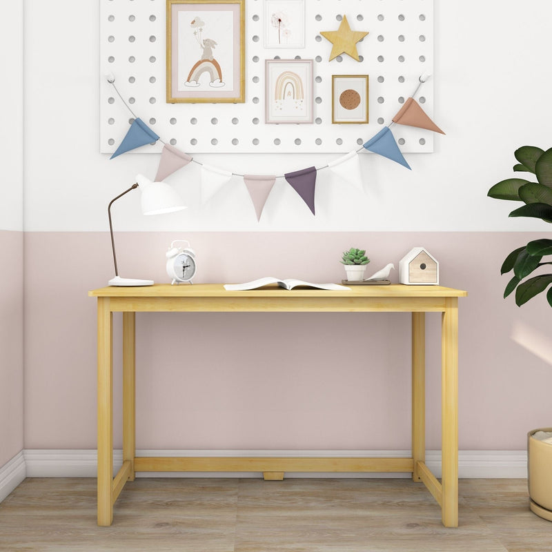 Modern light wood kids desk in pink and white nursery, minimalist children's study table with lamp, alarm clock, bunting, framed rainbow prints and potted plant