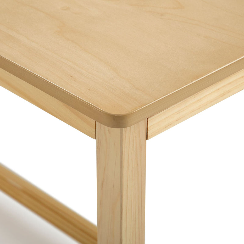 Close-up of light wood table corner with rounded edge, smooth natural finish and sturdy square leg