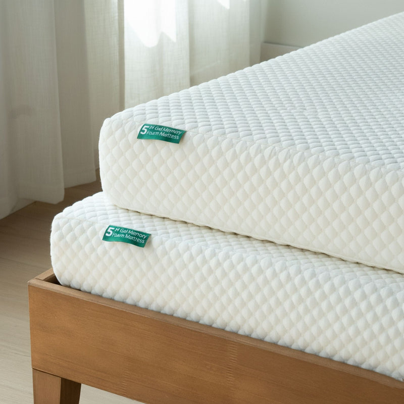 Two stacked 5-inch gel memory foam mattresses with white quilted covers on a wooden platform bed frame in a bright bedroom with sheer curtains