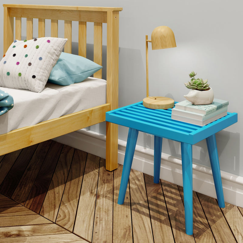 Modern bedroom corner with light wood bed frame, polka-dot pillow, blue nightstand, wooden table lamp and succulent on stacked books