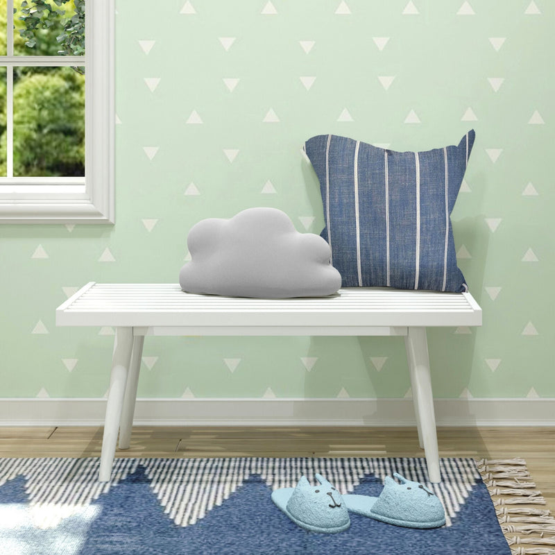 Nursery decor: white slatted bench by window with mint-green triangle wallpaper, gray cloud pillow, blue striped cushion and blue cat slippers on a patterned rug
