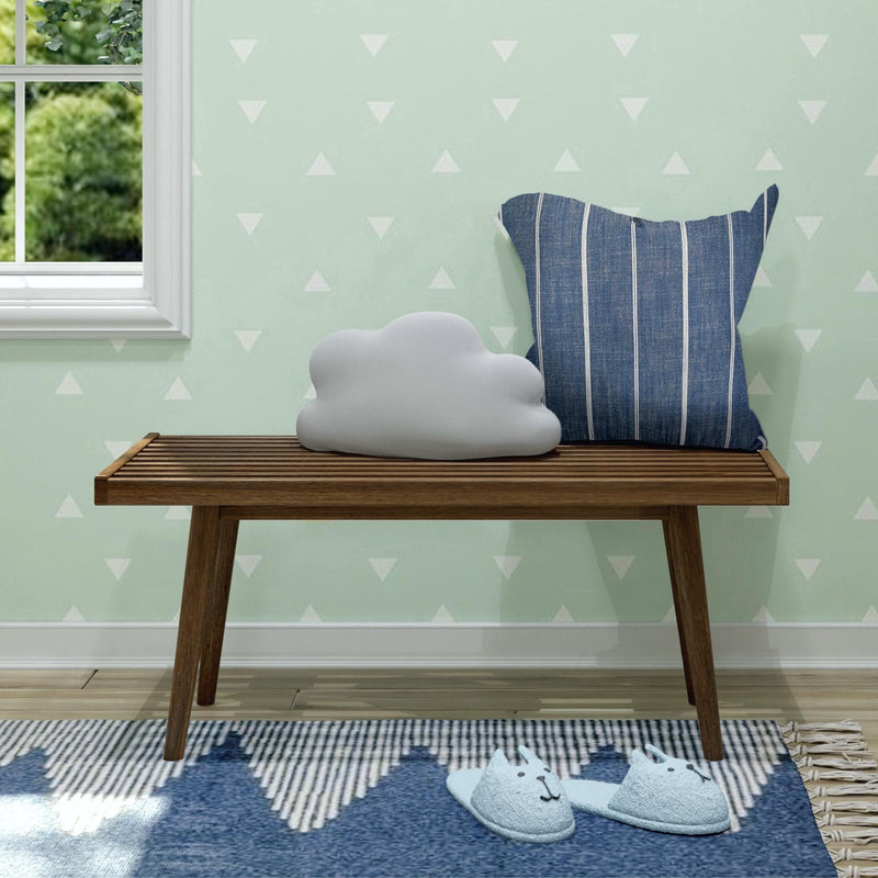 Nursery corner with mint green triangle wallpaper, wooden bench, cloud pillow, blue striped cushion and baby cat slippers on blue rug