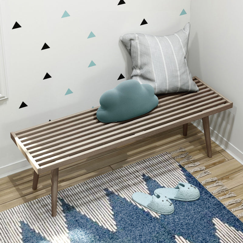Nursery wooden slatted bench with striped gray pillow and teal cloud cushion against black and teal triangle wall decals, blue slippers on patterned rug