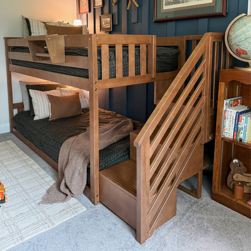 Solid wood bunk bed with built-in staircase in a modern kids' bedroom, pastel pink bedding, yellow accent pillows, rainbow rug and stuffed toy