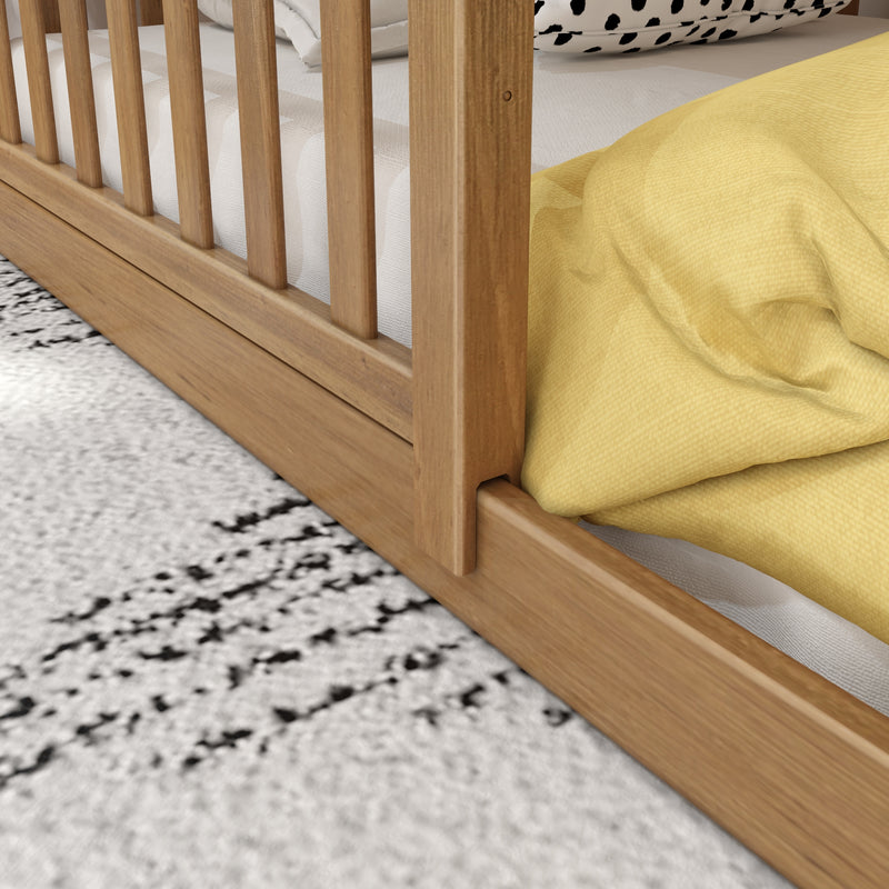 Close-up of natural oak slatted bed frame and platform base with white mattress, yellow duvet and black-and-white patterned pillow on textured rug