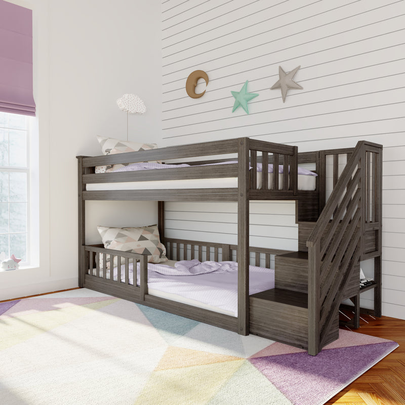 Gray wooden twin-over-twin bunk bed with staircase in a pastel kids' bedroom featuring shiplap wall, moon and star wall decor, patterned pillows and geometric rug