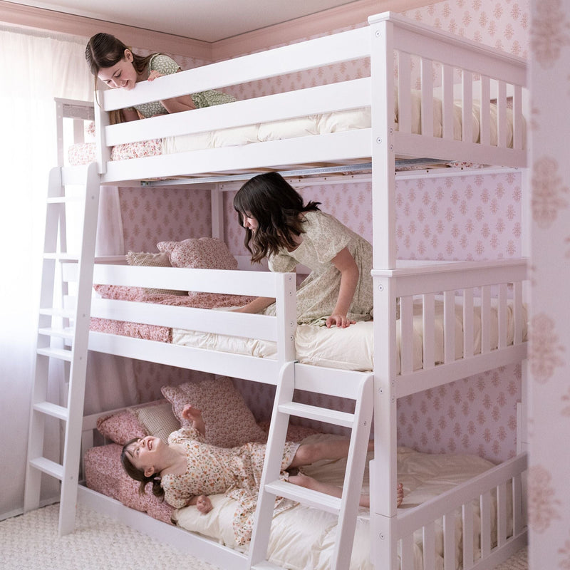 White wooden triple bunk bed with ladder in pastel pink floral kids bedroom, children playing on cozy beds with floral bedding