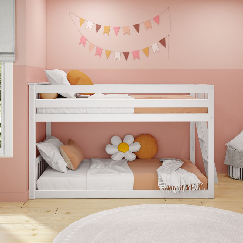 White wooden bunk bed in pink children's bedroom with peach bedding, daisy cushion, hanging bunting, ladder, hardwood floor and round rug