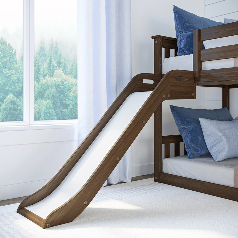 Wooden kids loft bunk bed with slide, blue pillows and white curtains by sunlit window overlooking trees — children's bedroom furniture