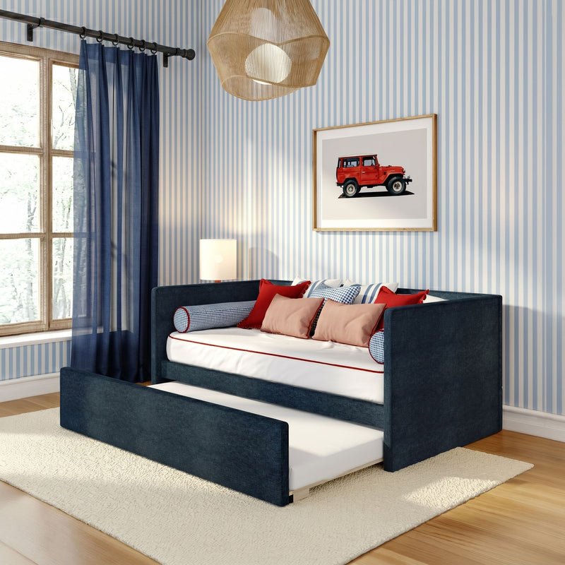 Modern nautical children's bedroom with navy daybed and pull-out trundle, blue-striped wallpaper, navy sheer curtains, red accent pillows and framed red jeep art