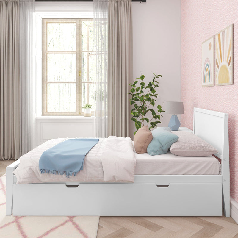 Sunlit pastel kids' bedroom with white storage bed and drawer, blue throw and decorative pillows, potted plant, pink patterned wallpaper and sheer curtains