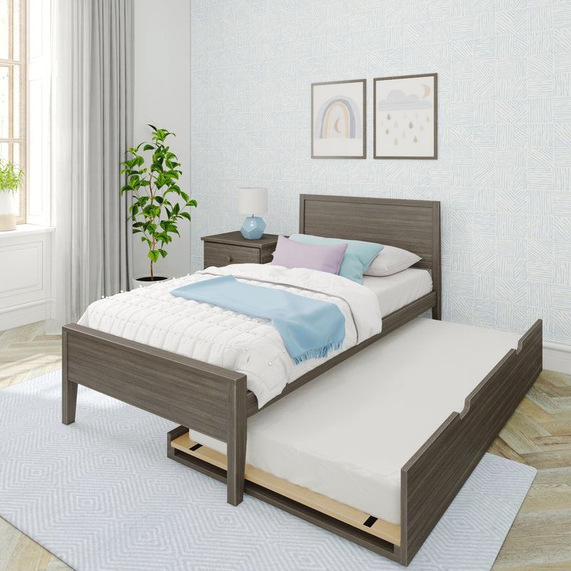 Gray wooden trundle bed in a modern kids' bedroom with pastel pillows and a light-blue throw, light-blue patterned wallpaper, framed rainbow and cloud wall art, bedside table with a blue lamp, potted plant and window with white curtains