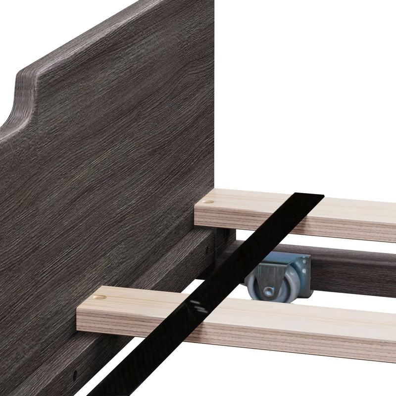Close-up of dark gray wood bed frame side rail with light wooden slats, metal caster wheel, metal bracket and black support strap