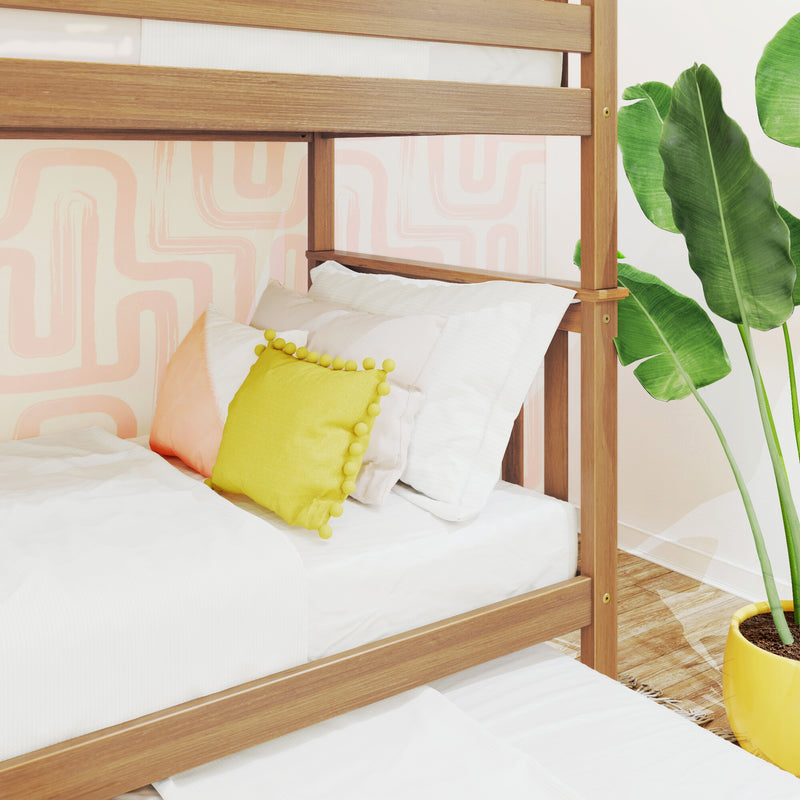 Wooden bunk bed with white bedding and yellow accent pillow in a pastel geometric kids' bedroom with tropical plant