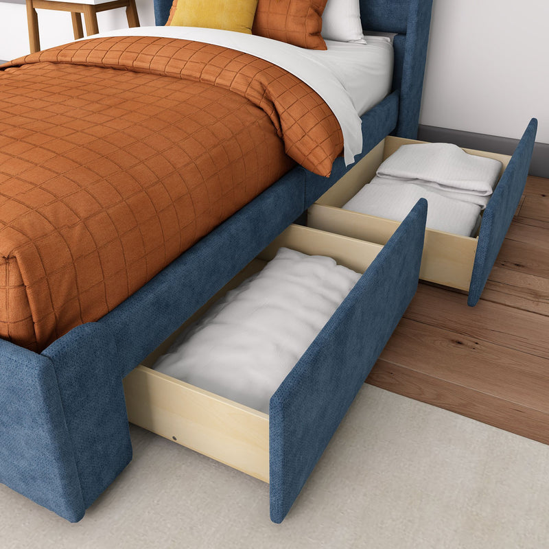 Blue upholstered storage bed with pull-out wooden drawers, orange quilted duvet and pillows on hardwood floor — modern bedroom storage solution