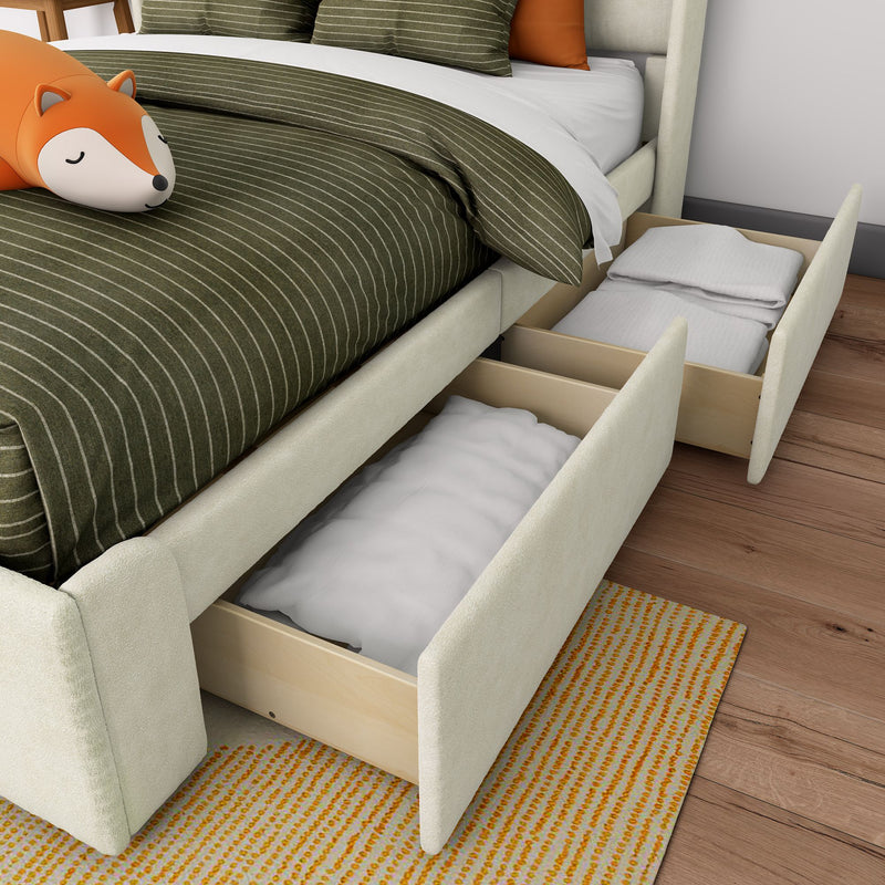 Under-bed storage drawers open in a modern bedroom revealing folded linens beneath an upholstered bed with olive green striped duvet and orange fox plush pillow
